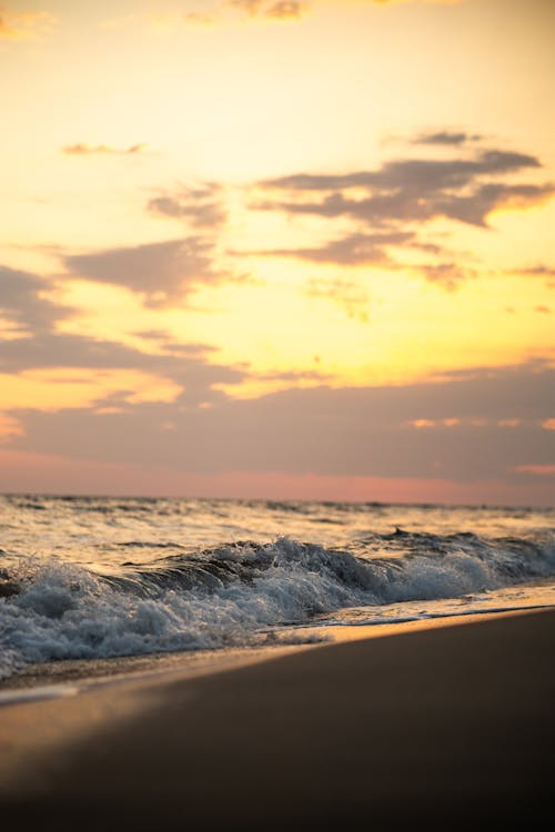 Free A sunset on the beach with waves crashing Stock Photo