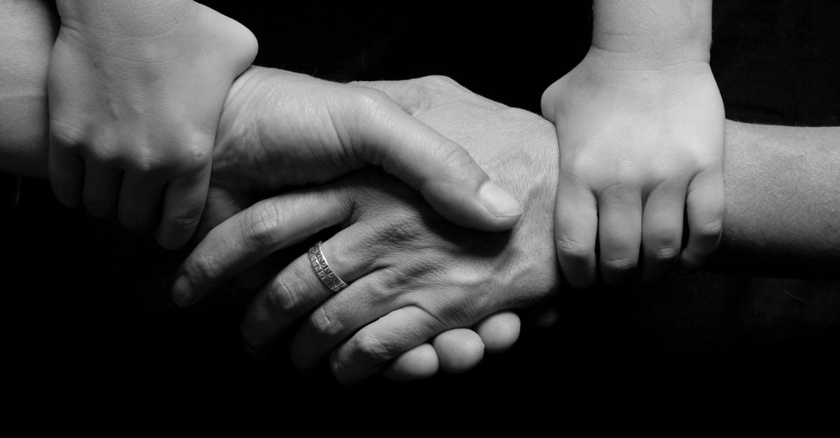 Monochrome image of a child's and adult's hands clasped together symbolizing trust and connection.