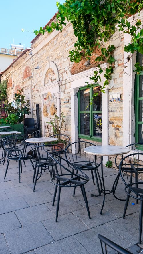 Free Idyllic outdoor cafe with metal seating against a rustic stone wall. Stock Photo