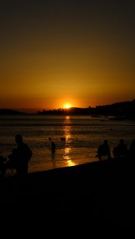 Tranquil sunset at the beach with silhouettes and tranquil water reflections.