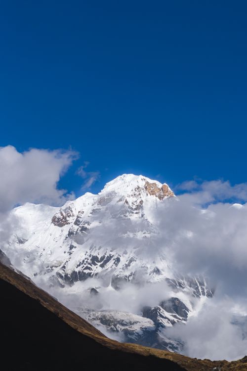 Free Stunning view of Machhapuchchhre in Nepal surrounded by clouds under a clear blue sky. Stock Photo
