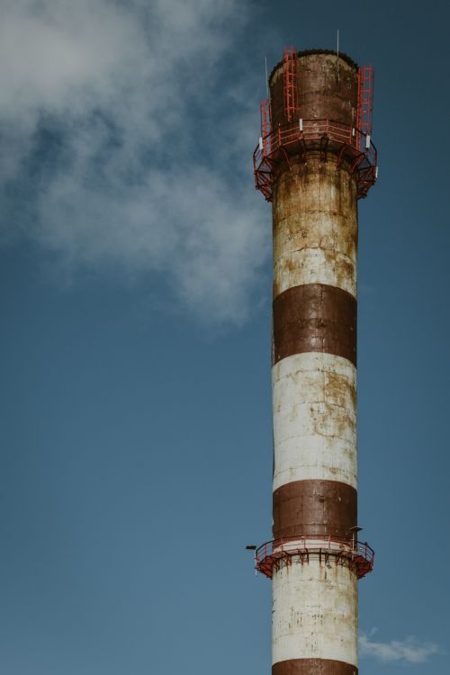 Free A tall industrial chimney releasing smoke, capturing environmental impact and air pollution. Stock Photo