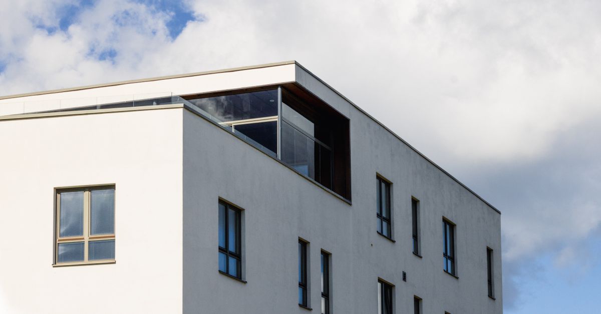 Minimalist white residential building under a partly cloudy sky in Tartu, Estonia.