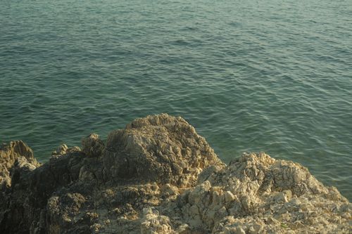 Free Explore the rugged beauty of rocks by the clear ocean shore with tranquil waters. Stock Photo