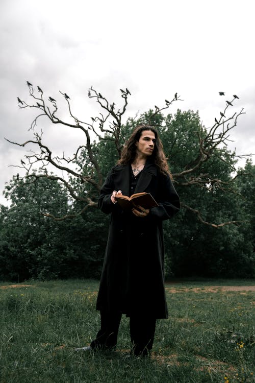 A woman in black coat standing in a field with trees