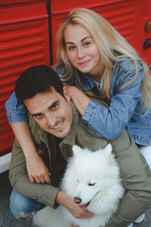 A couple posing with a dog in front of a red truck