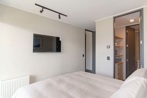 Free A modern bedroom featuring a cozy bed, wall-mounted TV, and minimalist decor. Stock Photo