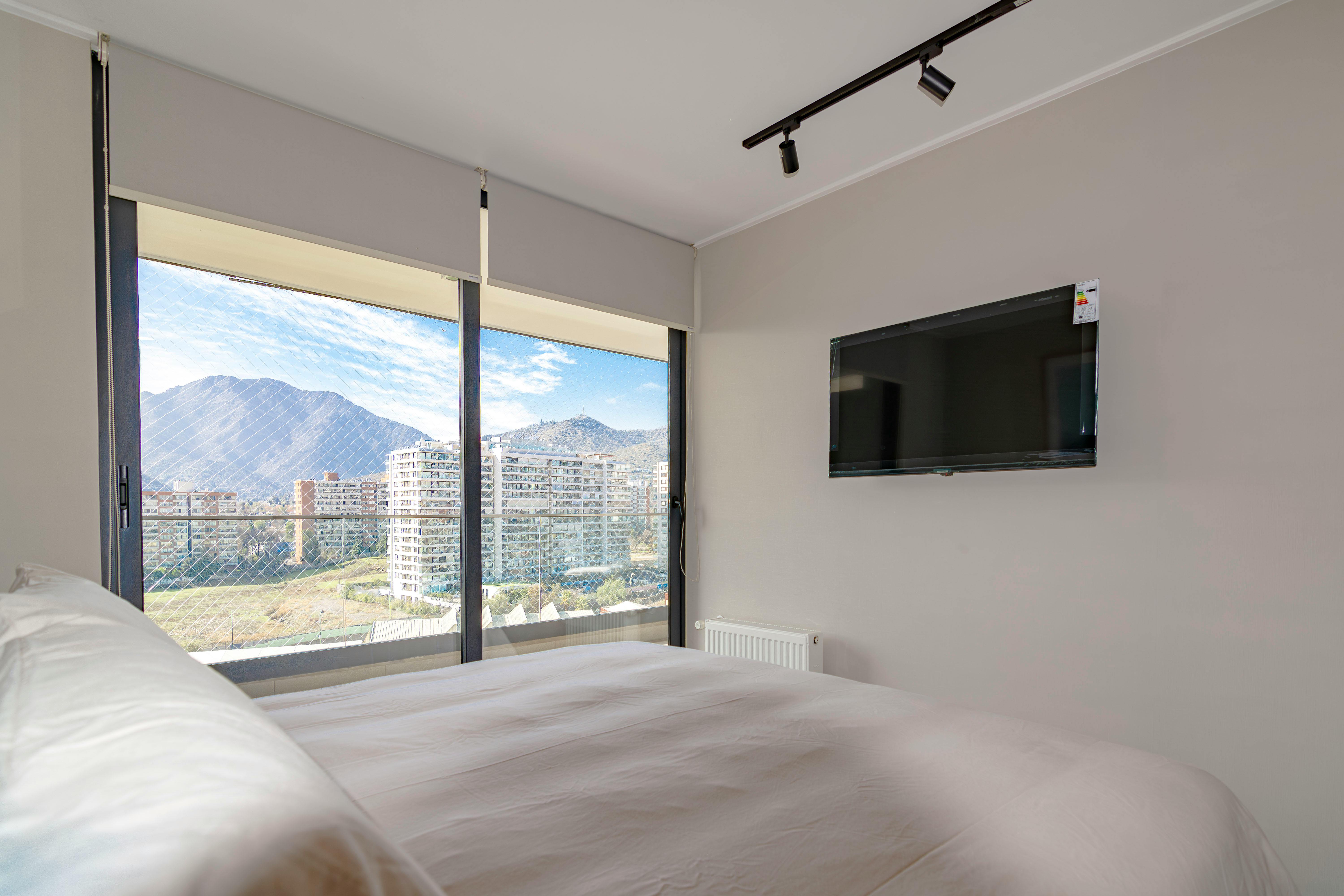 Cozy bedroom interior with a stunning mountain view and wall-mounted TV.
