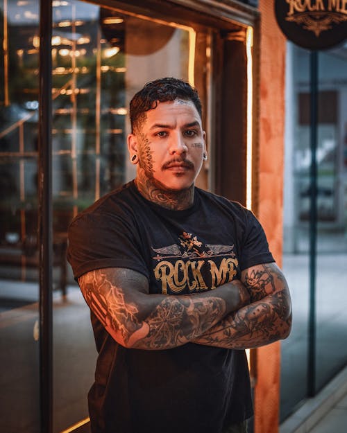 A man with tattoos standing in front of a bar