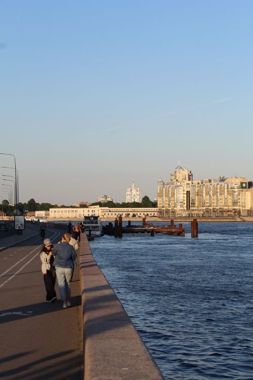 Free People enjoying a riverside stroll with city skyline in the background during day time. Stock Photo