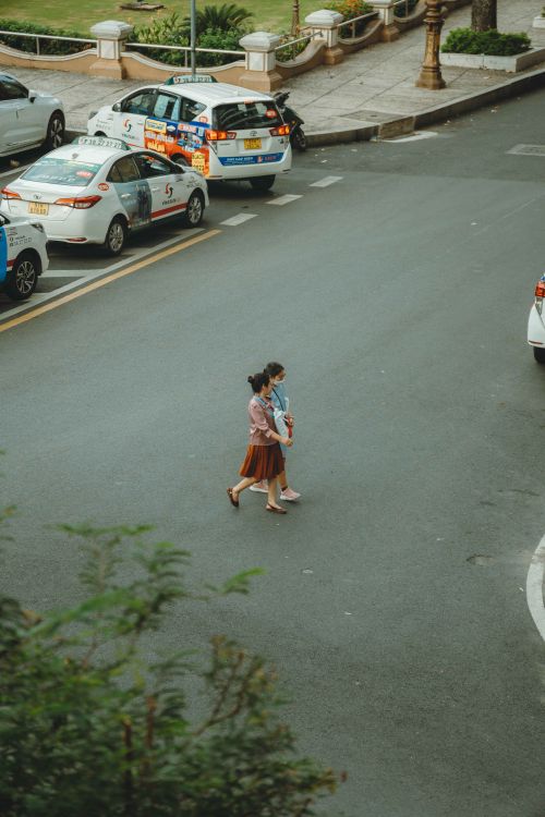 Free Aerial view of two women crossing the street among taxis in Ho Chi Minh City. Stock Photo
