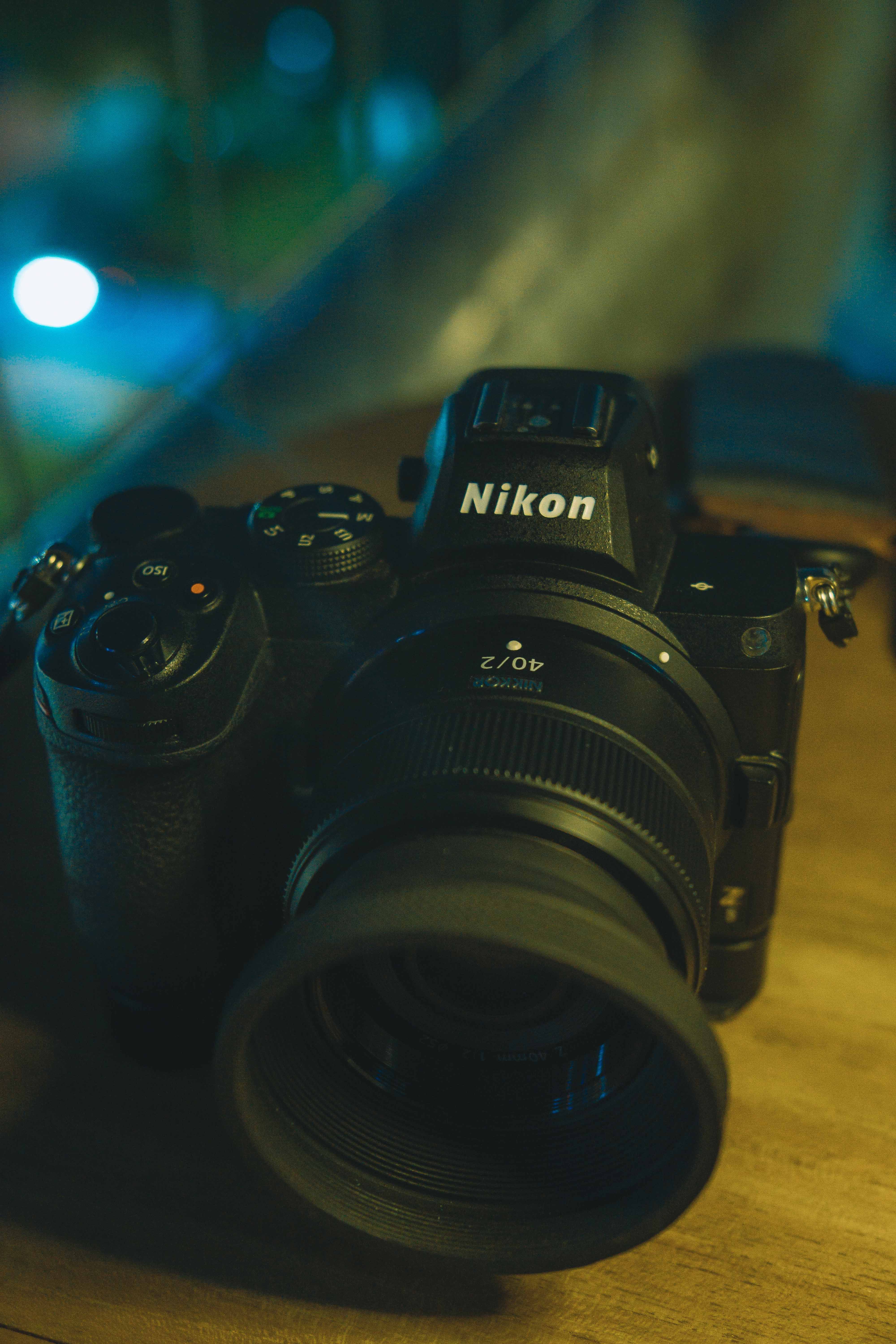 Nikon camera resting on a wooden surface with blurred background lighting.