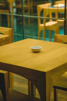 Modern wooden table with a single bowl in a stylish Vietnamese restaurant interior.