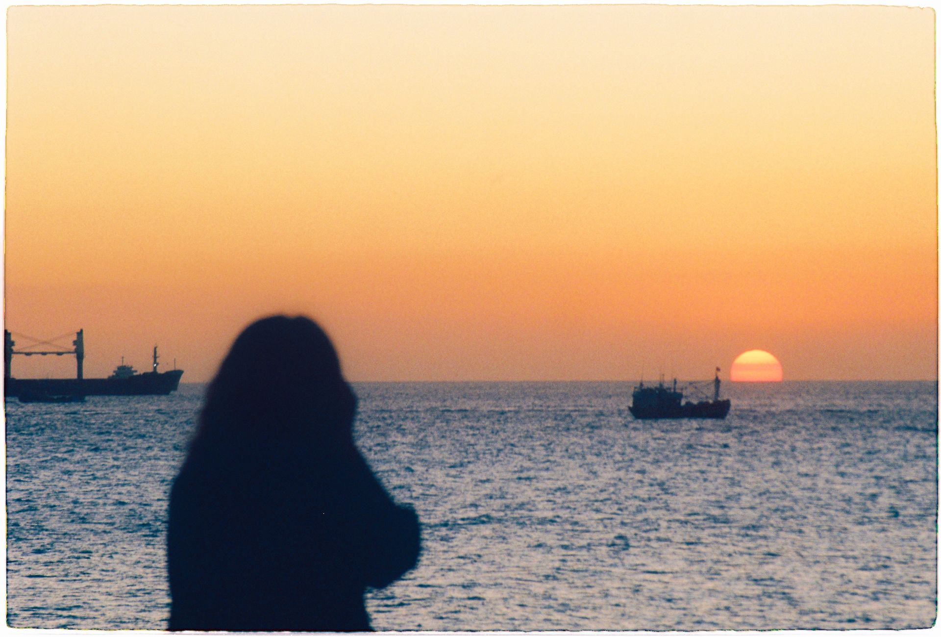 Silhouette of Ships and Woman on Sea Shore at Sunset