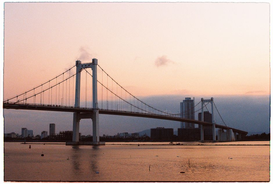 Scenic sunset over the bridge in Da Nang, Vietnam with city skyline.