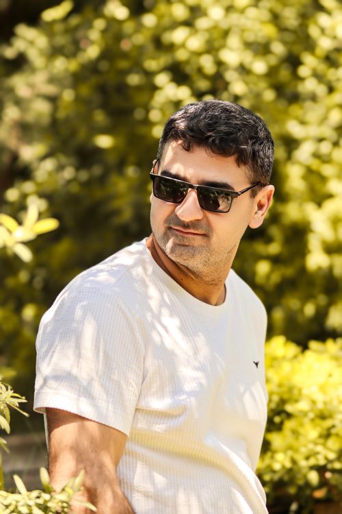 Free A stylish man wearing a white t-shirt and sunglasses enjoys a sunny day outdoors. Stock Photo