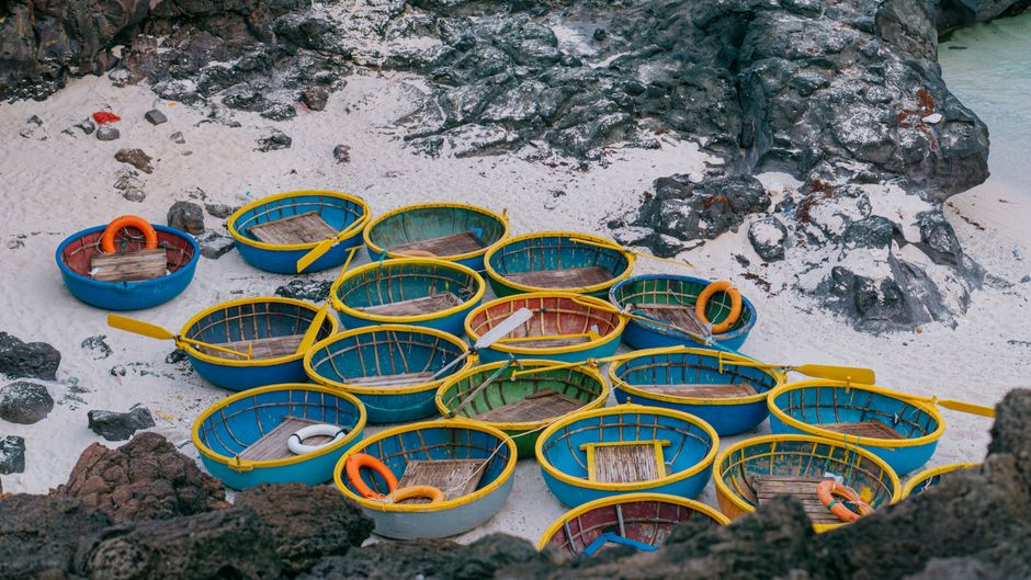 Cluster of vivid basket boats on a rocky shore in Quảng Ngãi, Vietnam, showing traditional marine architecture.