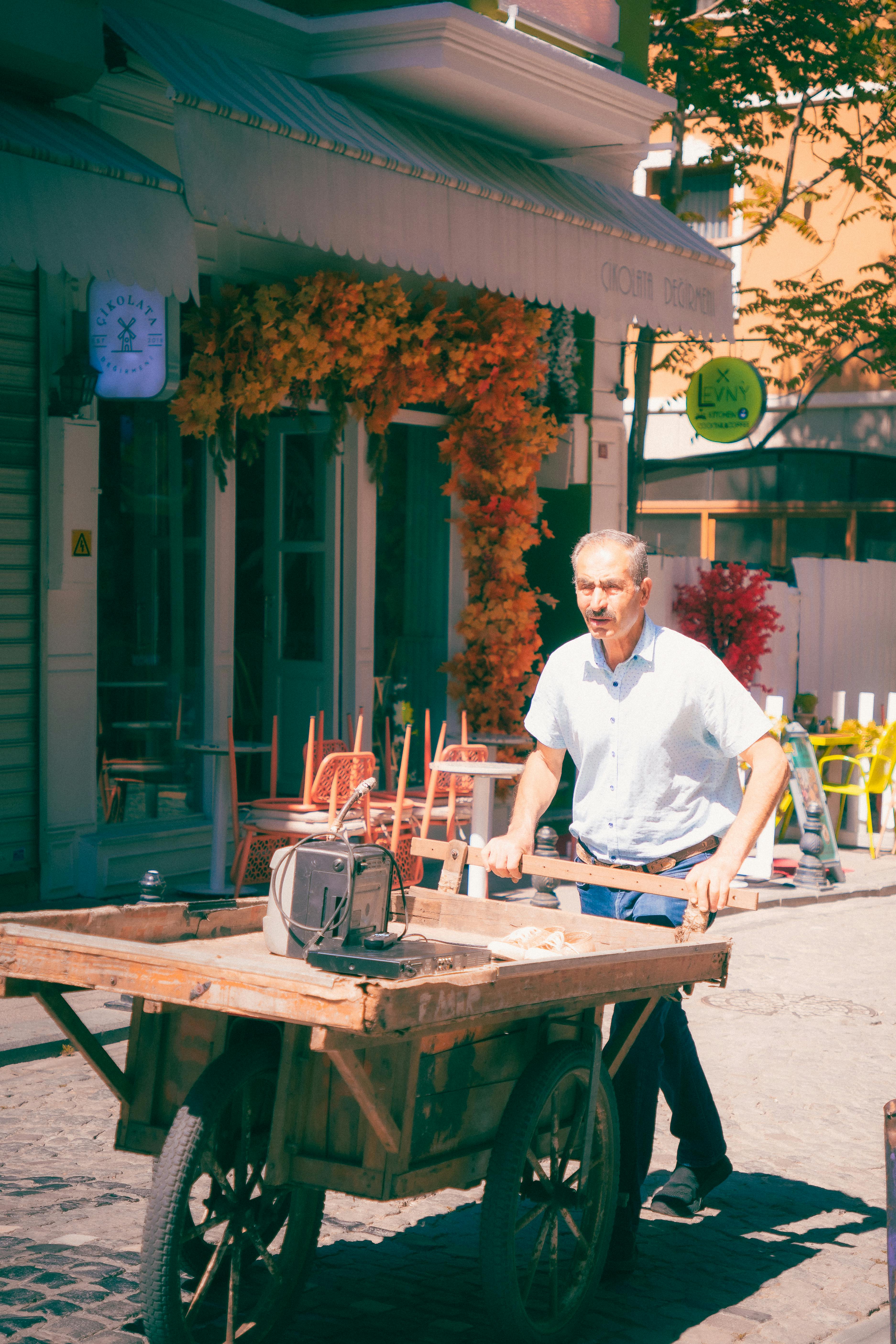 Elderly man pushing a wooden cart on a vibrant Istanbul street, capturing urban local life.