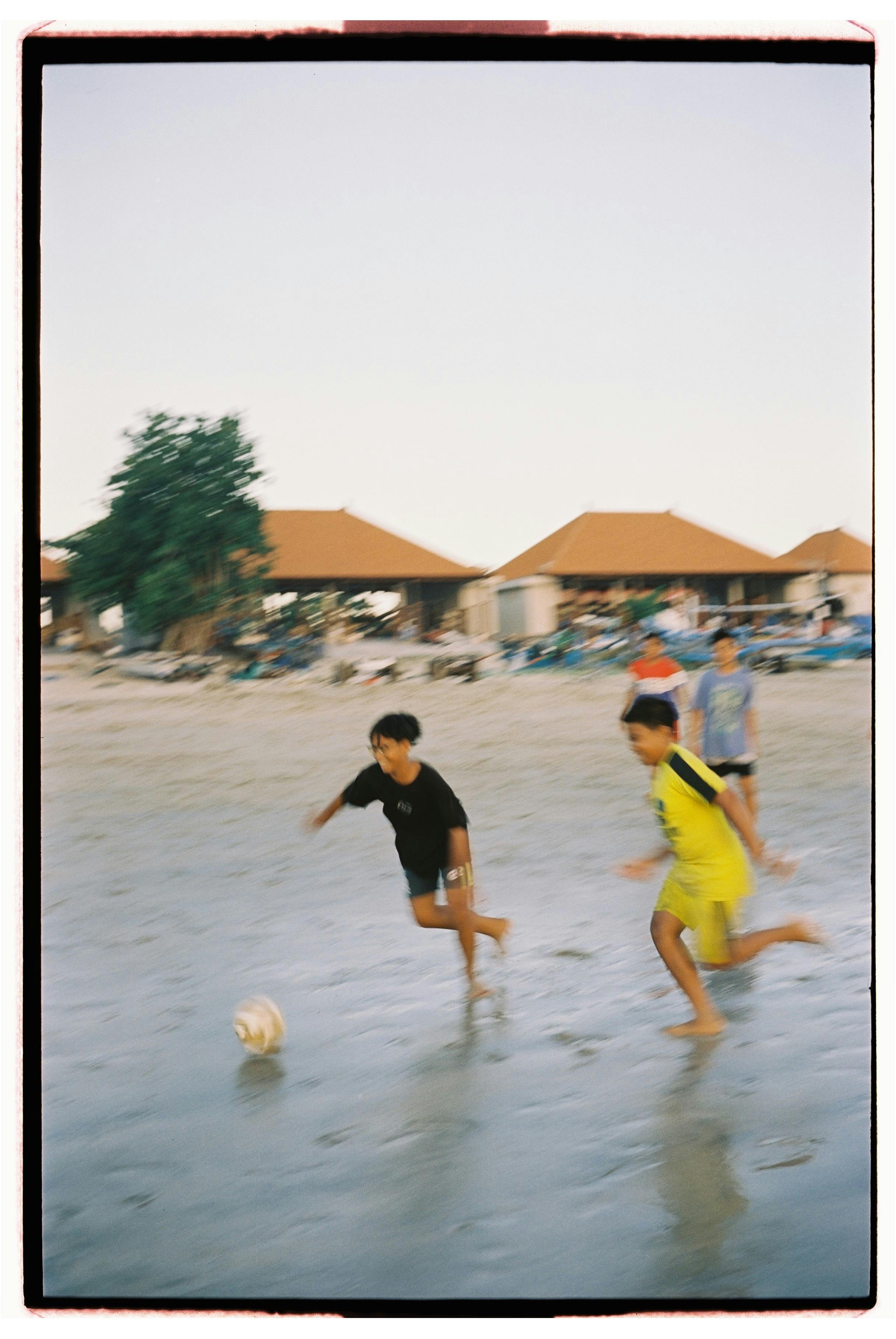 boys playing soccer on beach