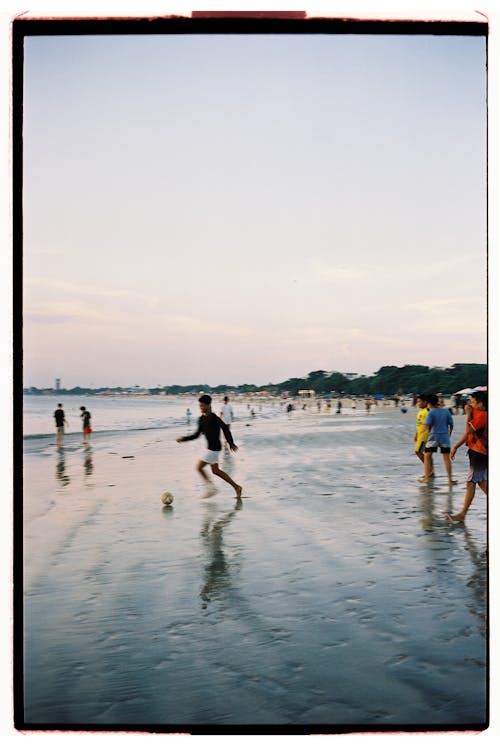 A group of people playing soccer on the beach