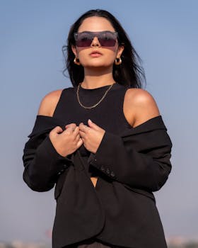 Elegant woman in sunglasses poses outdoors against a clear sky in Ciudad de México.