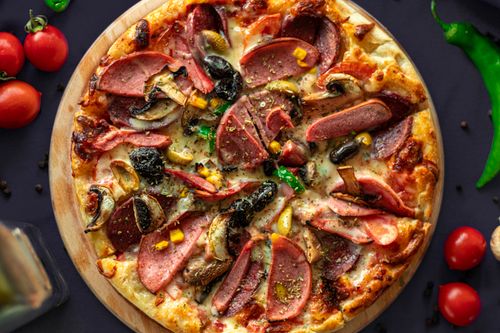 Free Top view of a freshly baked pizza with meat and vegetables, perfect for food photography lovers. Stock Photo