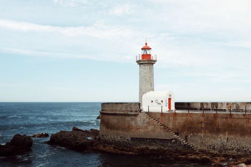 Free Lighthouse on Porto's rocky coastline guiding ships over the Atlantic Ocean. Stock Photo
