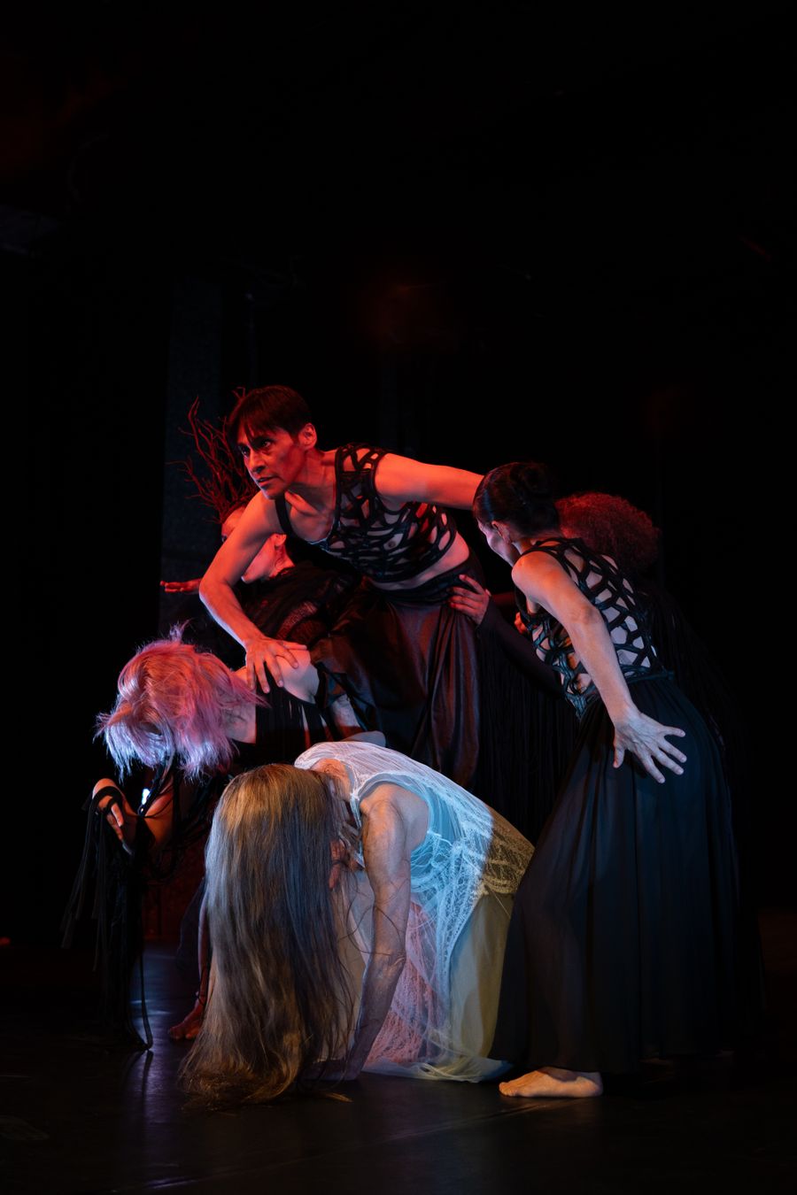 Dance ensemble performing an emotional piece on a dark stage
