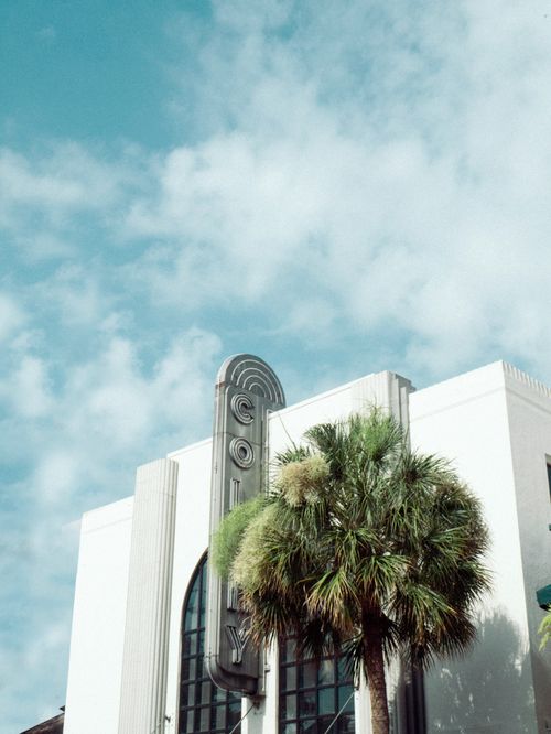 Free Art Deco building with palm tree in Winter Park, FL, under a clear blue sky. Stock Photo