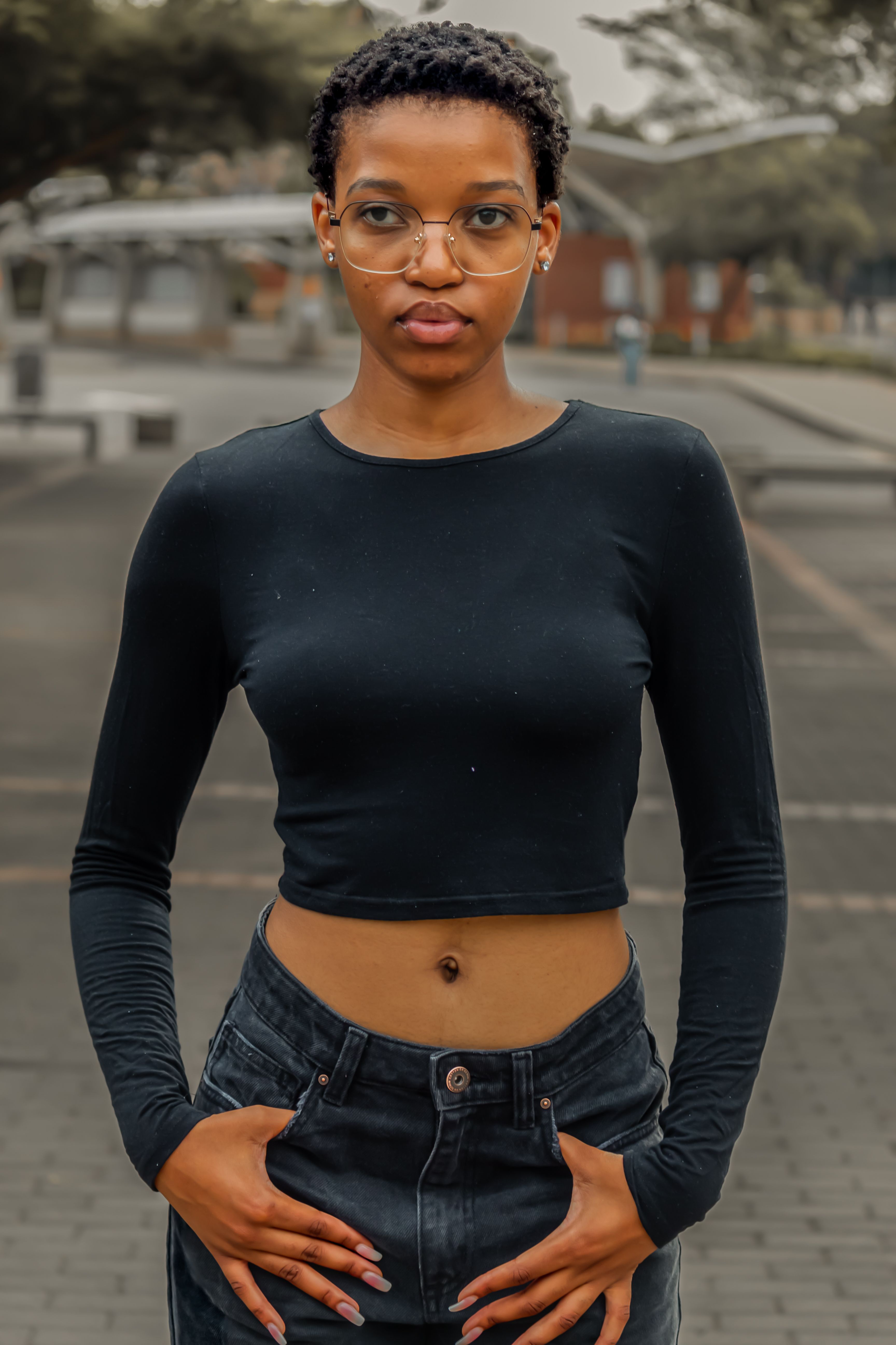 Stylish portrait of a young woman in an urban setting wearing a crop top.