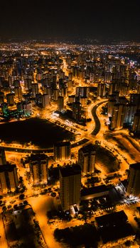 Aerial night view of a vibrant cityscape, illuminated streets and skyscrapers.