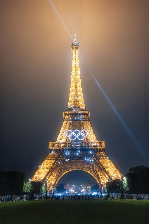   Eiffel tower illuminated at night with the rings of the paris 2024 olympic games in a foggy environment