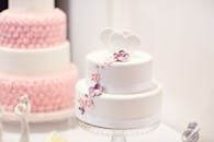 这款装饰精美的白色婚礼蛋糕，配有优雅的花卉设计，非常适合婚礼场合