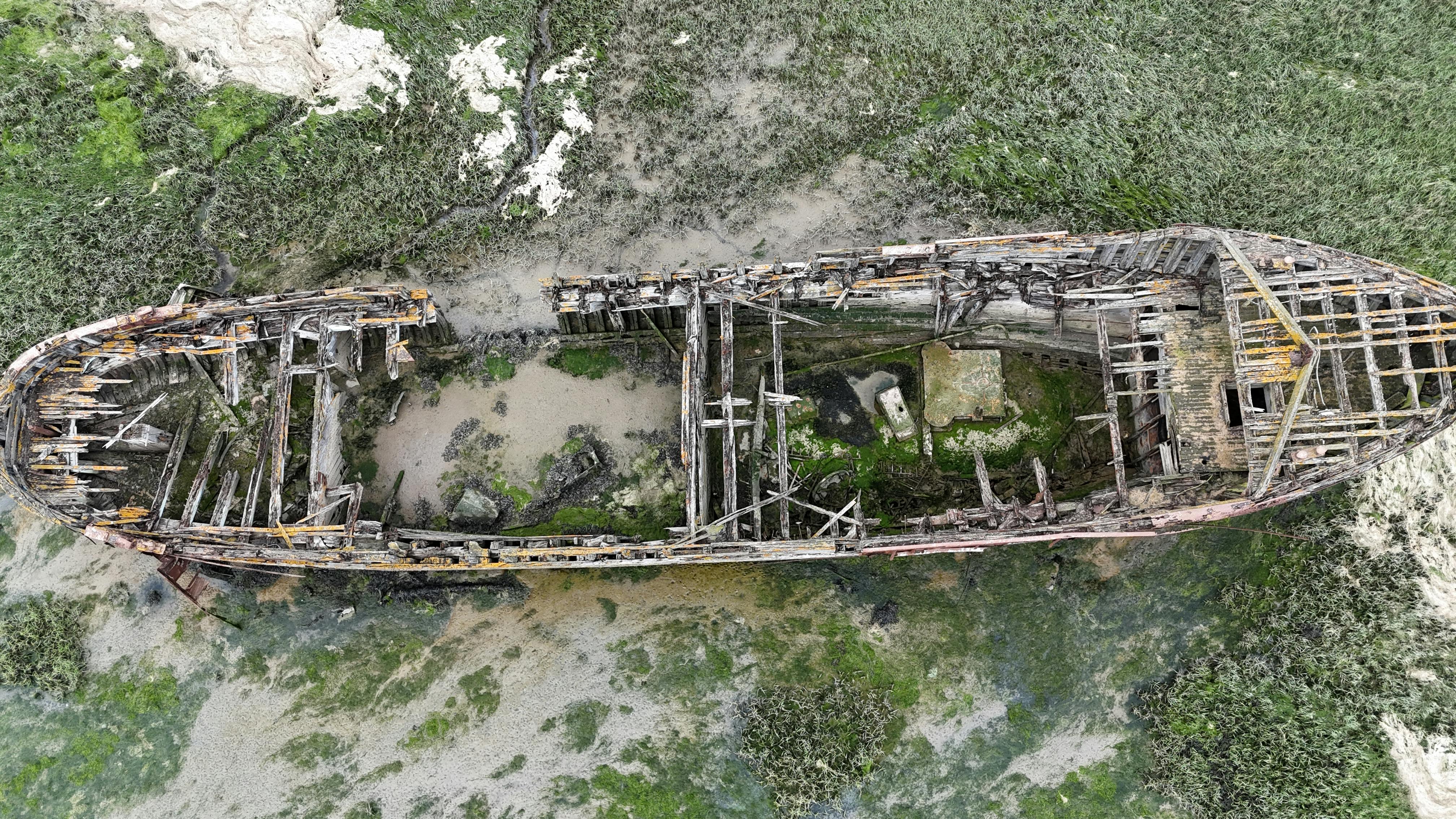 Aerial shot of an old wooden shipwreck in a swampy area of Gillingham, United Kingdom.