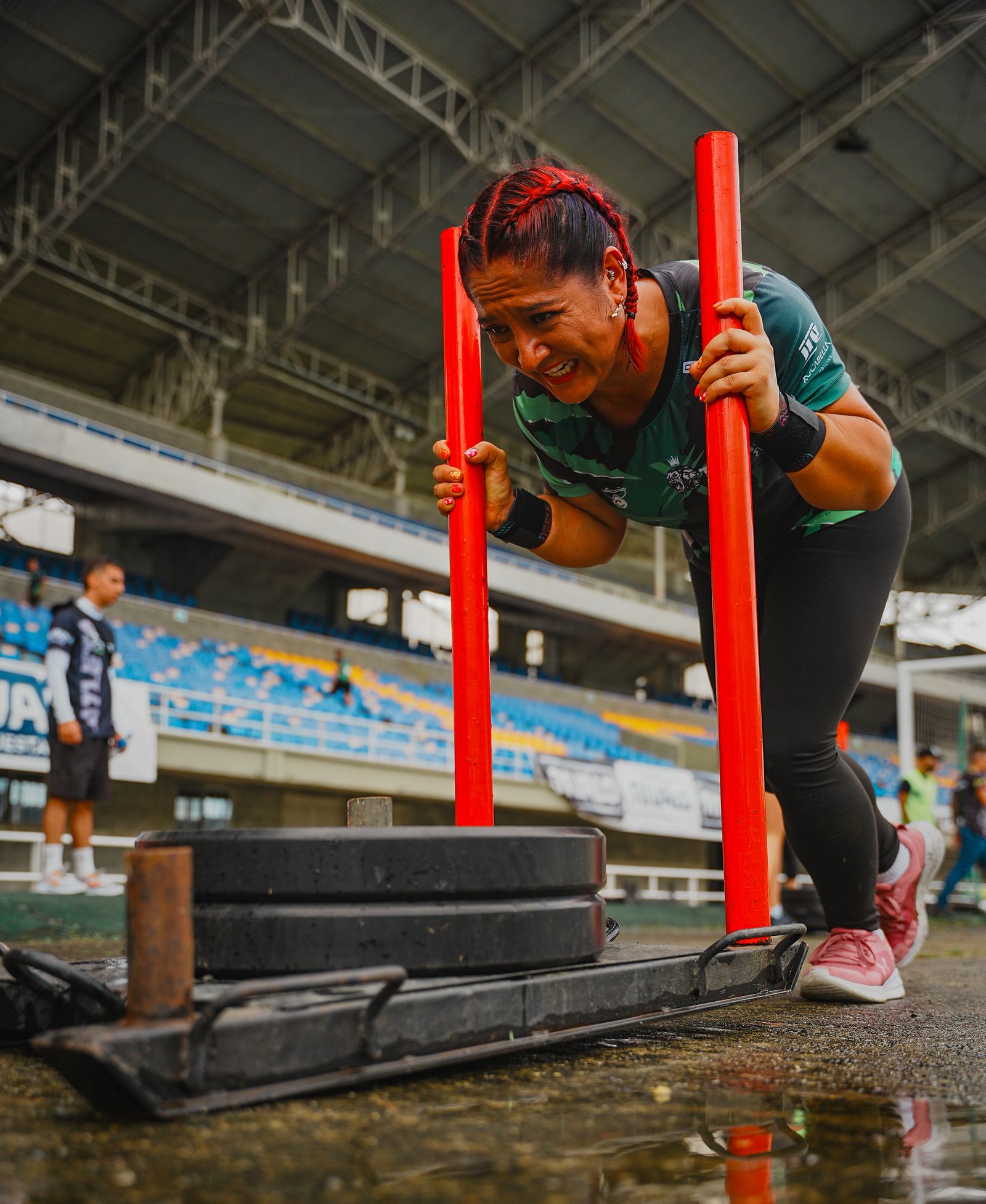 Woman athlete pushing a heavy sled in an outdoor fitness competition — the kind of high-output Hyrox station where 570mg sodium loss starts cramps.