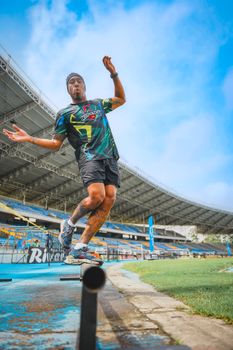 A focused athlete performing balance exercise on a beam outdoors in a stadium setting.