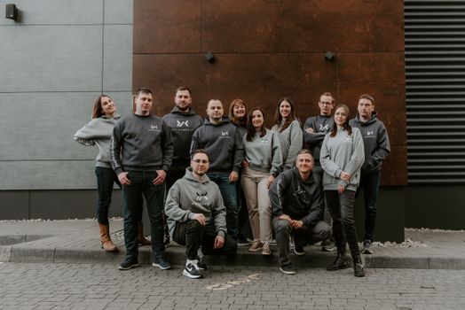 Group of diverse adults posing in matching hoodies against an urban backdrop.