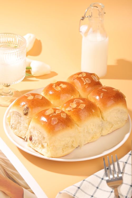 Free Close-up of freshly baked brioche rolls with almond garnish, served with milk. Stock Photo