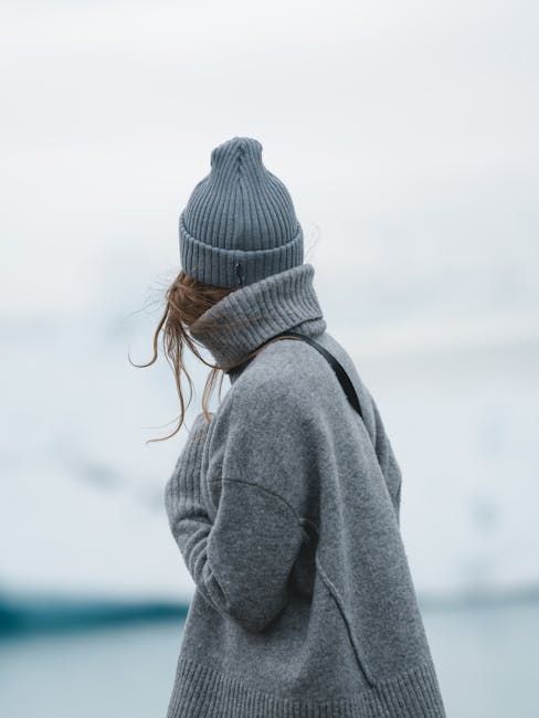 A woman gazes at the icy Icelandic landscape, wrapped in a cozy sweater and hat.