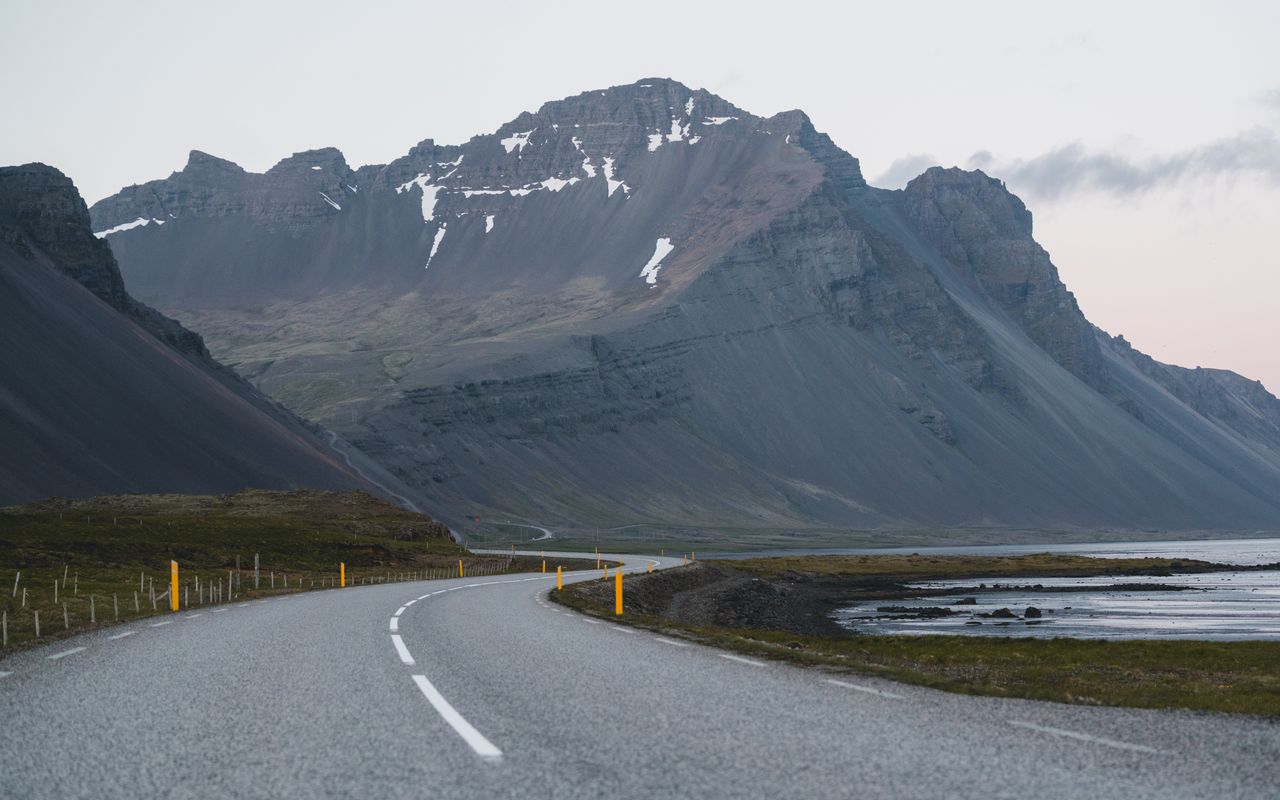 Empty winding road threading through mountains at moody blue hour