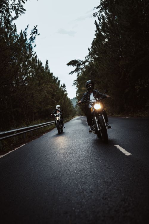Free Two motorcyclists riding on a scenic forest road, capturing the thrill of travel. Stock Photo