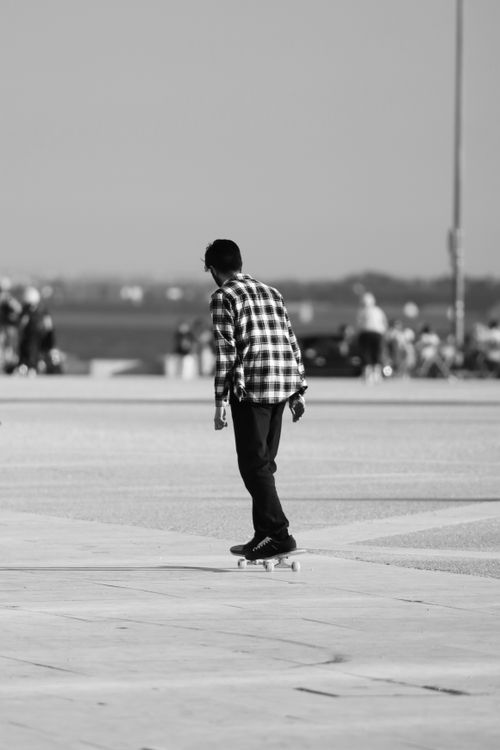 Free A man skateboards in a Lisbon cityscape, captured in monochrome for a classic feel. Stock Photo