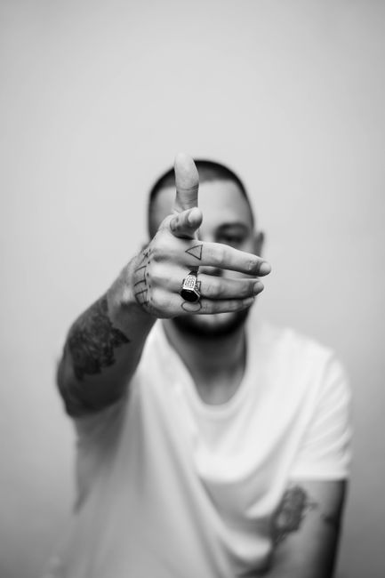 Monochrome portrait focusing on a tattooed hand gesture, creating an engaging and artistic composition.