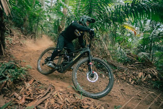 Man performing a thrilling mountain biking maneuver on a forest trail, showcasing speed and adventure.
