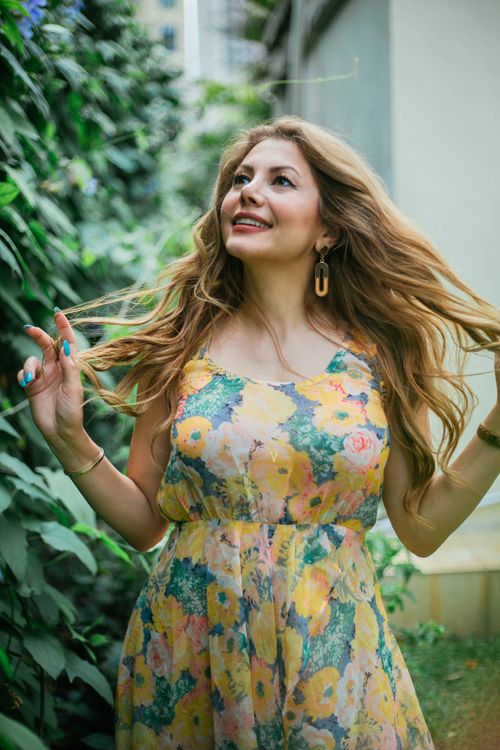 Free Smiling woman with long hair in floral sundress enjoying a summer day outdoors. Stock Photo