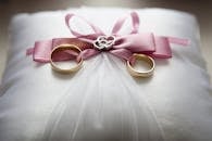 Selective Focus Photography of Silver-colored Engagement Ring Set With Pink Bow Accent on Throw Pillow