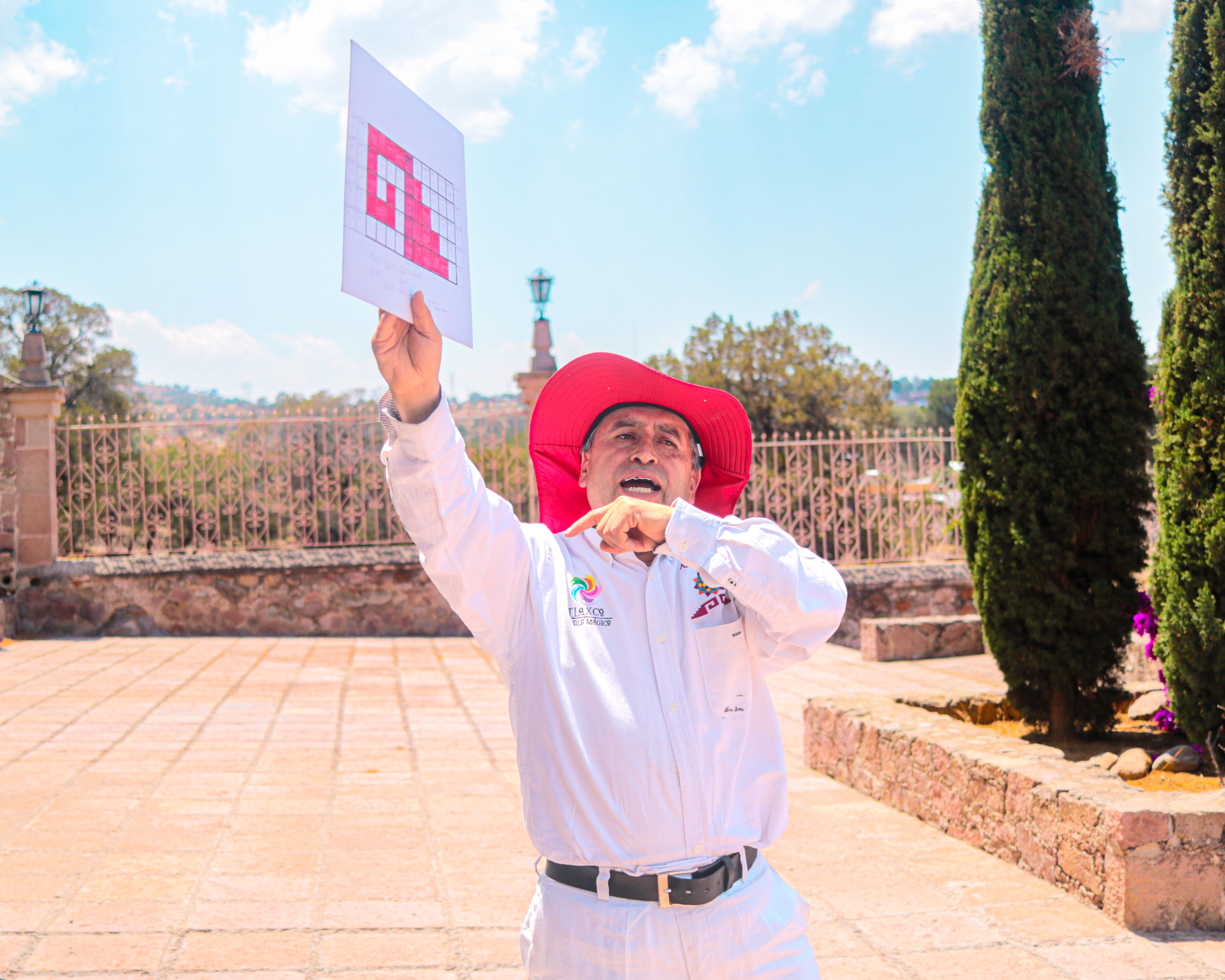 Senior man in white attire and red hat celebrating outdoors on a sunny day.
