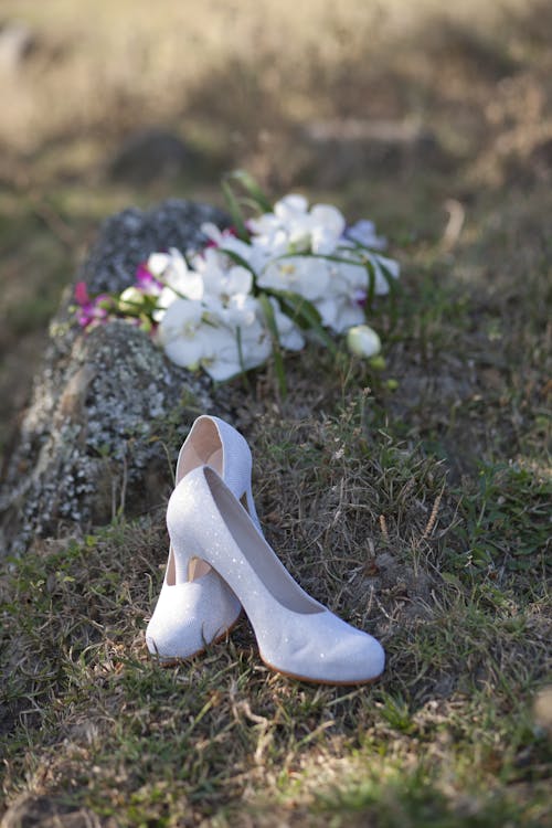 Pair of Heeled Shoes Near Flowers in Grass