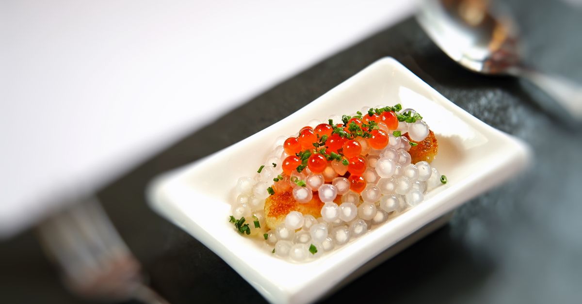 Prato de caviar gourmet luxuoso servido em um pequeno prato com apresentação artística em um ambiente de alta gastronomia.