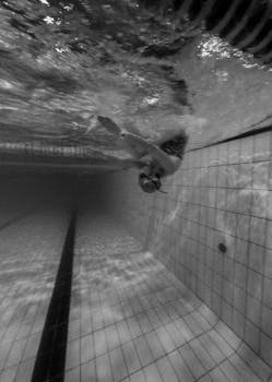 Dynamic underwater shot of a swimmer diving in a pool, showcasing elegant movement in black and white.